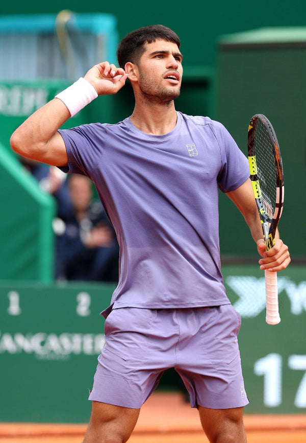 Tennis player mid-swing on court at night