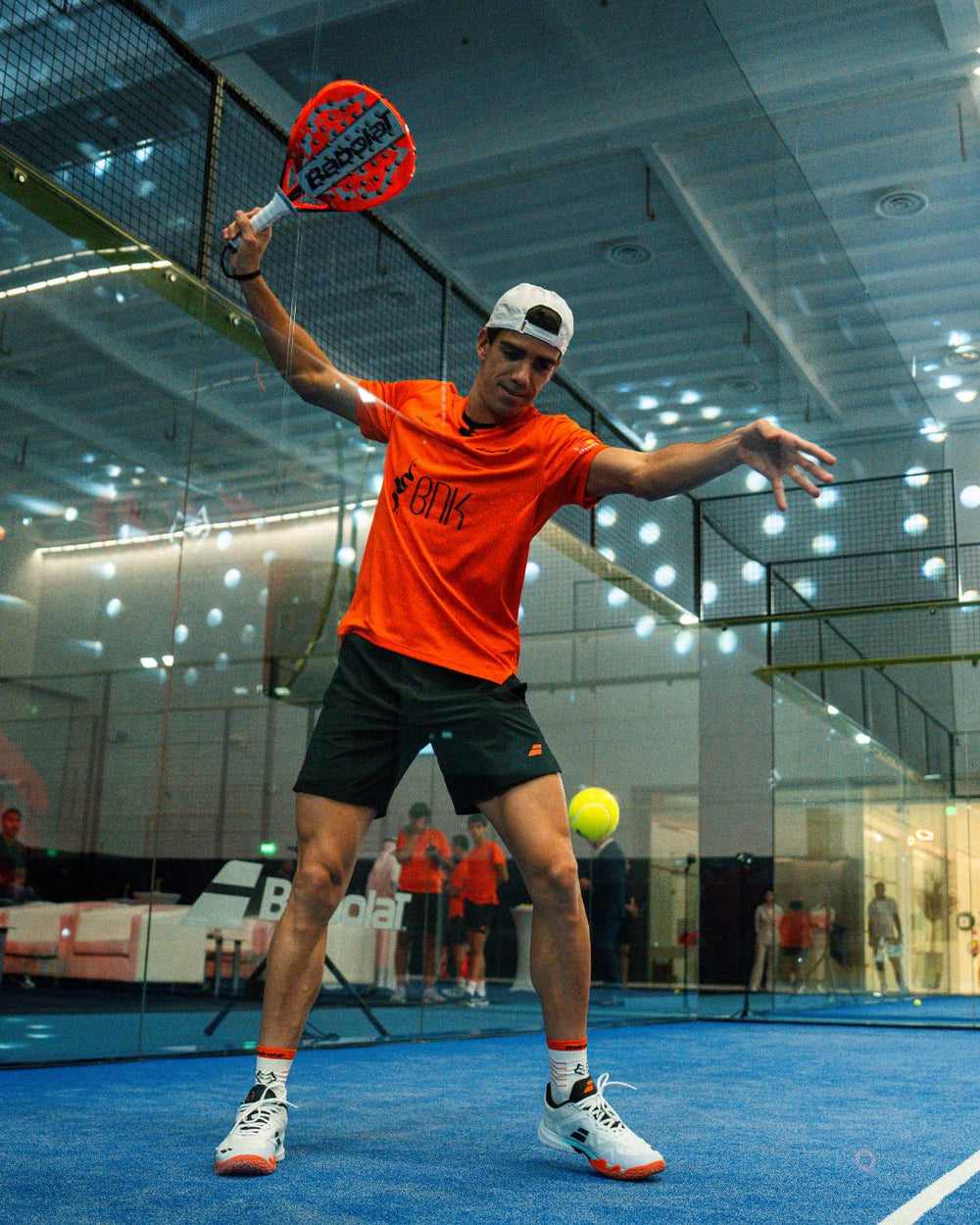 Padel player volleying near glass wall